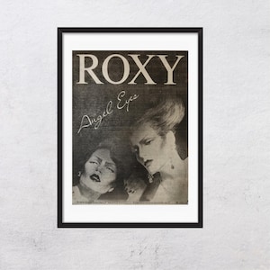 May include: Black framed vintage poster featuring the band Roxy. The poster has a black and white image of two women and the words "ROXY" and "Angel Eyes". The text "A new single from the LP 'MANIFESTO'" is also visible.