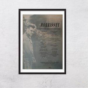 Puede incluir: Un póster enmarcado con una imagen en blanco y negro de Morrissey. El póster incluye el texto "MORRISSEY" y "November Spawned a Monster". Las letras están impresas en el lado derecho del póster.