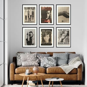 Puede incluir: Seis carteles de conciertos en blanco y negro enmarcados en una pared blanca. Los carteles muestran im&aacute;genes de Talking Heads, Nick Cave and the Bad Seeds, Prince and the Revolution, David Bowie, Tom Waits y una banda llamada The Pricks.