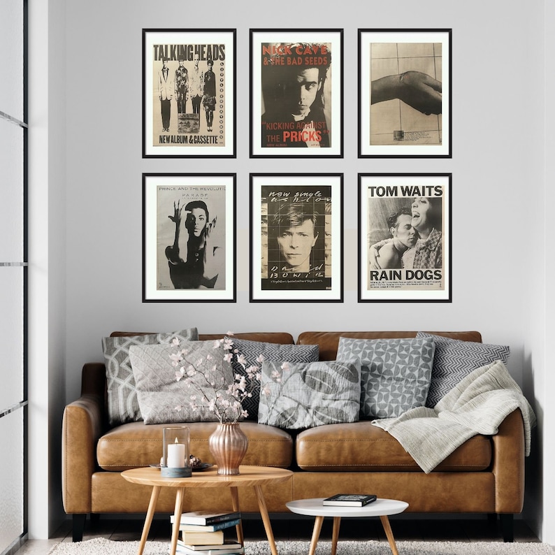 Puede incluir: Seis carteles de conciertos en blanco y negro enmarcados en una pared blanca. Los carteles muestran im&aacute;genes de Talking Heads, Nick Cave and the Bad Seeds, Prince and the Revolution, David Bowie, Tom Waits y una banda llamada The Pricks.