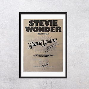 Könnte beinhalten: Gerahmtes Poster mit Stevie Wonders Single "Master Blaster Jammin'". Das Poster hat ein Retro-Design mit schwarzem Text auf beigem Hintergrund. Der Text enthält den Namen des Künstlers, den Songtitel und Albumdetails.