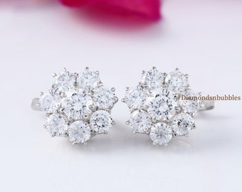 May include: A pair of silver earrings with a cluster of clear round cubic zirconia stones in a flower shape.