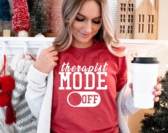 May include: Red t-shirt with white text that reads "therapist mode off" with a white toggle switch graphic. The switch is in the off position.