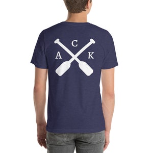 May include: A navy blue t-shirt with a white graphic of two crossed paddles with the letters "A C K" on them.
