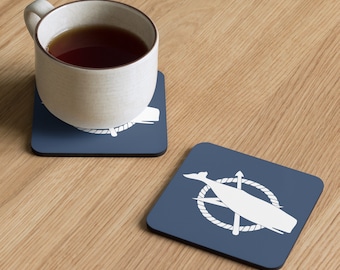 May include: Two blue square coasters with a white whale and harpoon design. The whale is inside a rope circle with a harpoon crossing through it.