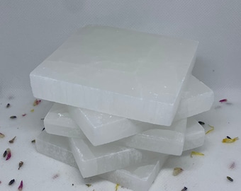 May include: A stack of four white selenite coasters. The coasters are smooth and have a natural, slightly textured surface.