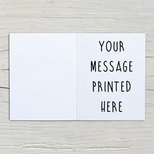 May include: A white greeting card shown open, featuring a blank left panel and a right panel with the black text "YOUR MESSAGE PRINTED HERE" in a simple sans-serif font. The card is displayed flat, showcasing its clean, minimalist design.