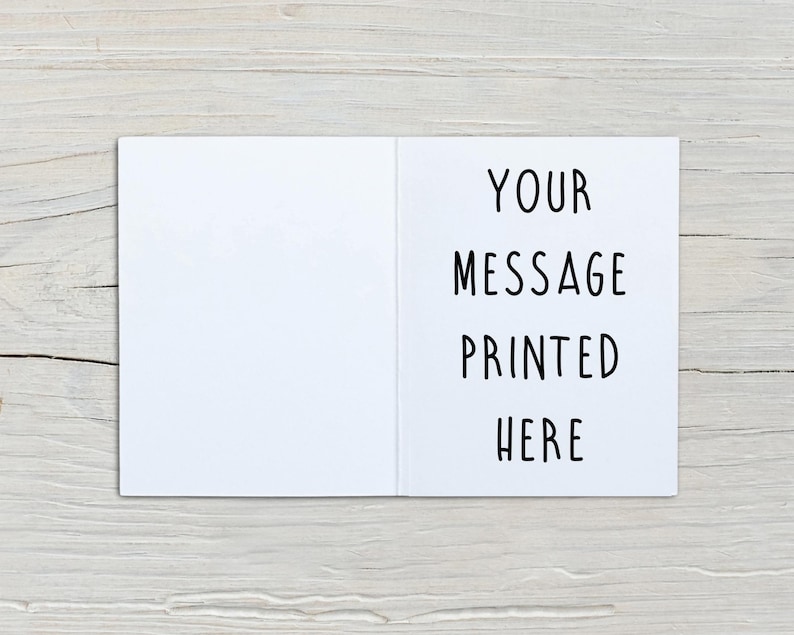 May include: A white greeting card shown open, featuring a blank left panel and a right panel with the black text "YOUR MESSAGE PRINTED HERE" in a simple sans-serif font. The card is displayed flat, showcasing its clean, minimalist design.