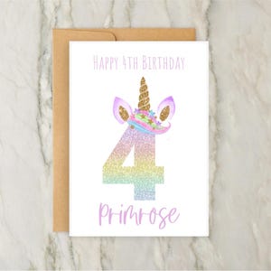 May include: A birthday card with a unicorn theme. The card features the text "Happy 4th Birthday" and the name "Primrose". The number 4 is in a rainbow glitter design, and the unicorn has a gold horn and ears.