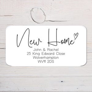 May include: White card with black text that reads "New Home" with a small heart symbol. The card also includes the name John & Rachel, the address 25 King Edward Close, Wolverhampton, WV1 2DS.