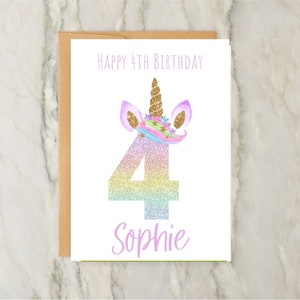 May include: A birthday card with a unicorn theme. The card features the text "Happy 4th Birthday" at the top, a large number "4" in a rainbow glitter design, and the name "Sophie" at the bottom. The unicorn has a gold horn and purple ears.
