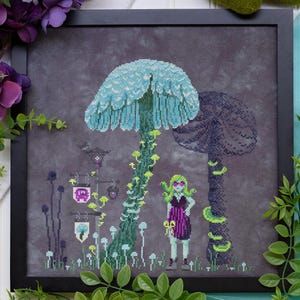 May include: Cross-stitch art in a black frame depicts a fantasy scene with large mushrooms, a figure, and stylized plants. The mushrooms are teal and purple, with a figure in a purple dress. The background is a dark gray.