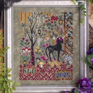 Puede incluir: Obra de arte de punto de cruz en un marco plateado. El diseño presenta un unicornio negro con una melena rosa, de pie cerca de un árbol con hojas de color otoñal. La obra incluye el texto "KLH" y el año "2025" en una fuente decorativa, con un patrón floral y damasco.