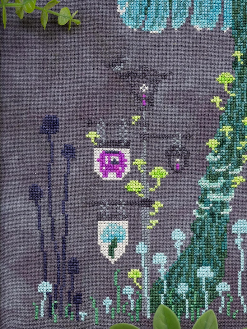 May include: Cross-stitch design featuring a whimsical scene with stylized mushrooms, a street lamp with purple and blue lanterns, and a tree. The color palette includes shades of purple, blue, green, and white, creating a fantasy theme.