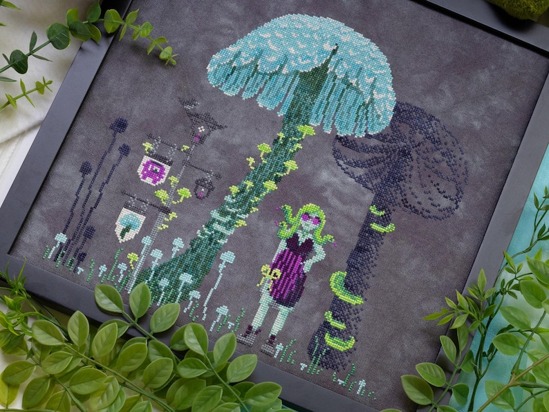 May include: Cross-stitch art featuring a fantasy scene with large mushrooms in shades of blue and green. A figure with green hair and sunglasses stands near the mushrooms. The artwork is framed in a black frame.