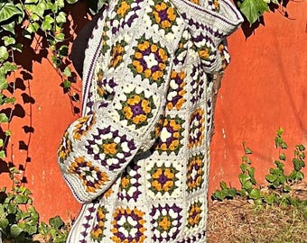 May include: A hooded cardigan crocheted in a granny square pattern with white, purple, green, and orange yarn.
