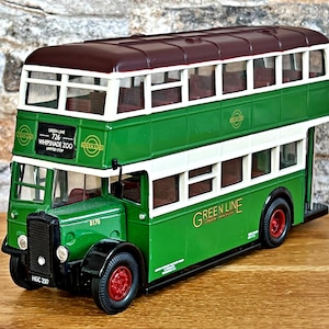Può includere: Modello di autobus a due piani verde e bianco con tetto marrone. L'autobus ha le scritte "Green Line" e "Whipsnade Zoo" sul lato. Le ruote sono rosse.