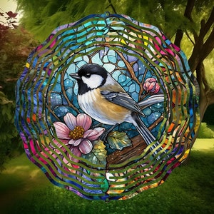 Peut inclure: Un mobile à vent en métal coloré avec un motif de vitrail représentant un oiseau bleu perché sur une branche avec des fleurs roses. Le mobile à vent est composé de plusieurs couches de métal qui tournent au vent.