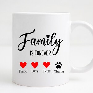 K&ouml;nnte beinhalten: Wei&szlig;e Keramiktasse mit schwarzem Text "Family is Forever" und vier roten Herzen mit den Namen David, Lucy, Peter und einem Pfotenabdruck mit dem Namen Charlie darunter.