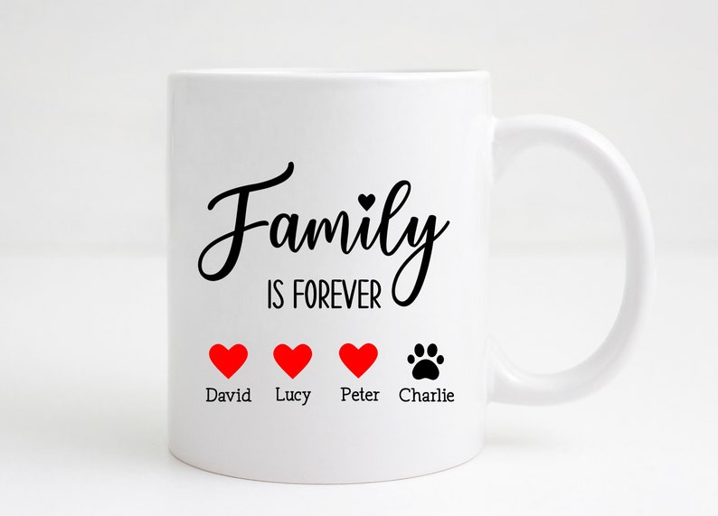 K&ouml;nnte beinhalten: Wei&szlig;e Keramiktasse mit schwarzem Text "Family is Forever" und vier roten Herzen mit den Namen David, Lucy, Peter und einem Pfotenabdruck mit dem Namen Charlie darunter.