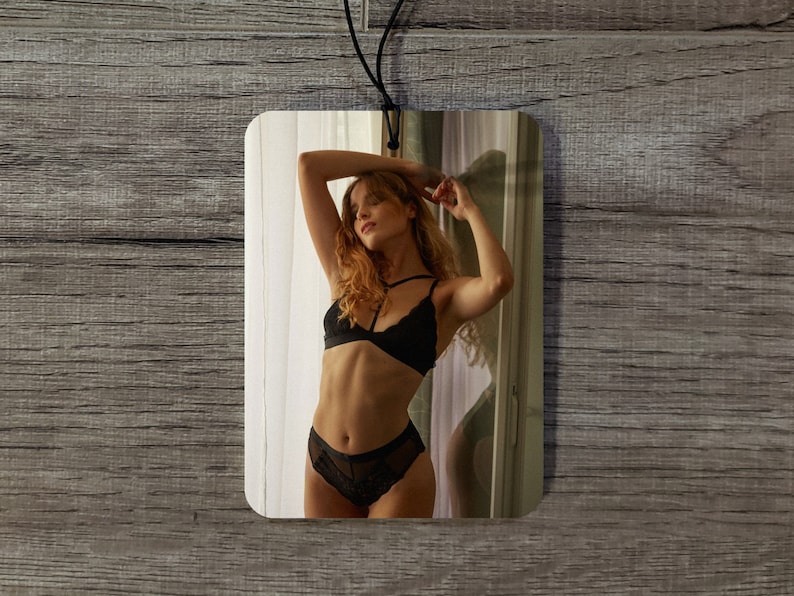 May include: A black lace lingerie set with a halter top and a high-waisted bottom. The model is standing in front of a window with white curtains.