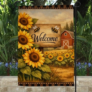 May include: A rectangular garden flag featuring a wooden sign with the word Welcome in black script, flanked by two bees. The scene depicts a field of yellow sunflowers and a red barn under a soft sky, framed by a brown and black checkered border.