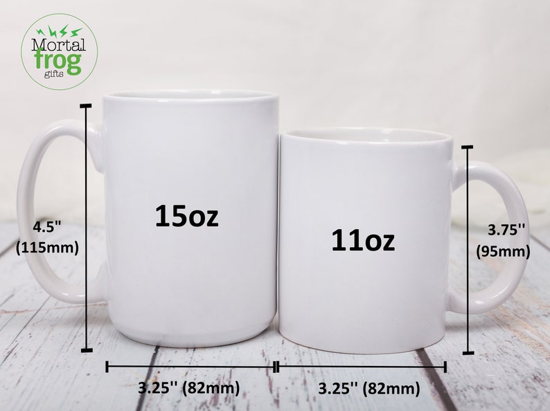K&ouml;nnte beinhalten: Zwei wei&szlig;e Keramikbecher, einer mit 15oz und einer mit 11oz, mit Ma&szlig;en in Zoll und Millimetern. Die Becher stehen auf einer Holzoberfl&auml;che.