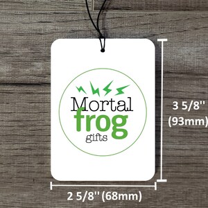 May include: White car air freshener with a green circle logo that says "Mortal frog gifts" with lightning bolts around the circle. The air freshener is 3 5/8 inches tall and 2 5/8 inches wide.