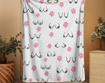 May include: White fleece blanket with a repeating pattern of black outlines of breasts and pink flowers.
