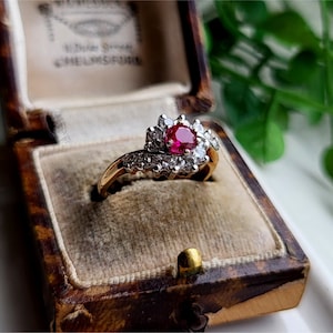 May include: A gold ring with a ruby and diamonds set in a vintage style. The ring is in a brown velvet ring box.