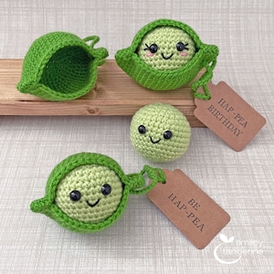 May include: Three crocheted pea pod toys with happy faces. One pea pod is open, one is closed, and one is a single pea. Two brown gift tags with the text "Hap-Pea Birthday" and "Be Hap-Pea" are included.