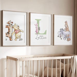 May include: Three framed wall art prints featuring Winnie the Pooh characters. The left print shows Tigger and Pooh. The center print features a large green letter L, Piglet, and the name Lottie. The right print shows Eeyore, Roo, and Kanga.