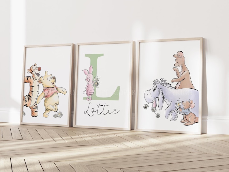 May include: Three framed wall art prints featuring Winnie the Pooh characters. The left print shows Tigger and Pooh. The center print features Piglet, a large green letter L, and the name Lottie. The right print shows Eeyore, Kanga, and Roo.