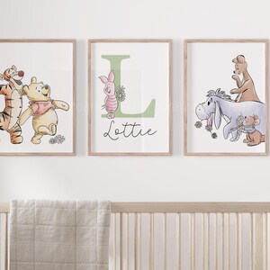 May include: Three framed wall art prints featuring Winnie the Pooh characters. The left print shows Tigger and Pooh. The center print displays a large green letter L, Piglet, and the name Lottie. The right print depicts Eeyore, Kanga, and Roo.
