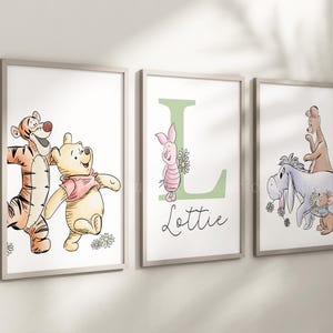 May include: Three framed wall art prints featuring Winnie the Pooh characters. The first shows Tigger and Pooh, the second a green letter L with Piglet and the name Lottie, and the third Eeyore, Kanga, Roo, and Rabbit with flowers.