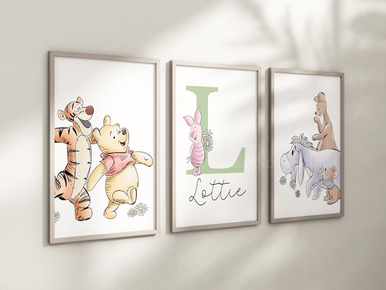 May include: Three framed wall art prints featuring Winnie the Pooh characters. The first shows Tigger and Pooh, the second a green letter L with Piglet and the name Lottie, and the third Eeyore, Kanga, Roo, and Rabbit with flowers.