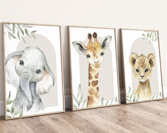 May include: Three framed wall art prints featuring watercolor illustrations of a baby elephant, a giraffe, and a lion cub. Each print displays a central animal against a beige arch background with green leaf accents on a white backdrop.