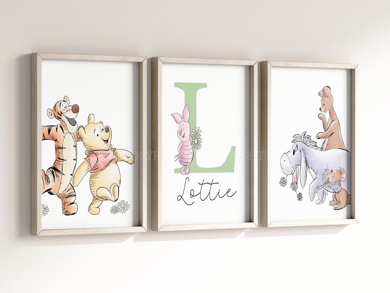 May include: Three framed wall art prints featuring Winnie the Pooh characters. The left print shows Tigger and Pooh. The center print displays a large green letter L with Piglet and the name Lottie. The right print shows Eeyore, Roo, and Roo.