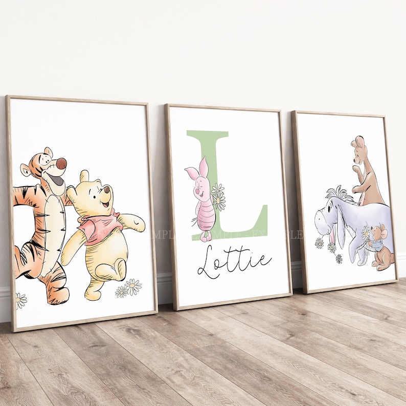 May include: Three framed wall art prints featuring Winnie the Pooh characters. The first shows Tigger and Pooh, the second a large green letter L with Piglet and the name Lottie, and the third Eeyore, Kanga, and Roo with daisies.
