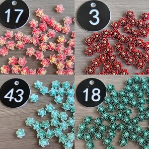 May include: A collection of small, multi-petaled flower-shaped embellishments in four distinct color groups: pink and yellow, deep red, light blue, and dark green. Each group is labeled with a black circular tag numbered 17, 3, 43, or 18.