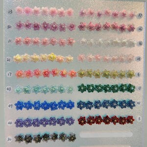 May include: A display board featuring rows of small, multi-colored flower-shaped cabochons, each with a central bead. The rows are labeled with numbers 13, 50, 11, 21, 17, 43, 49, 44, 30 on the left and 37, 26, 16, 28, 6, 18, 25, 3 on the right.