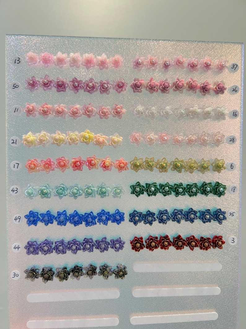 May include: A display board featuring rows of small, multi-colored flower-shaped cabochons, each with a central bead. The rows are labeled with numbers 13, 50, 11, 21, 17, 43, 49, 44, 30 on the left and 37, 26, 16, 28, 6, 18, 25, 3 on the right.
