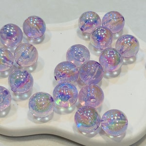 May include: A collection of iridescent purple glass beads. The beads are round and have a shimmery finish.