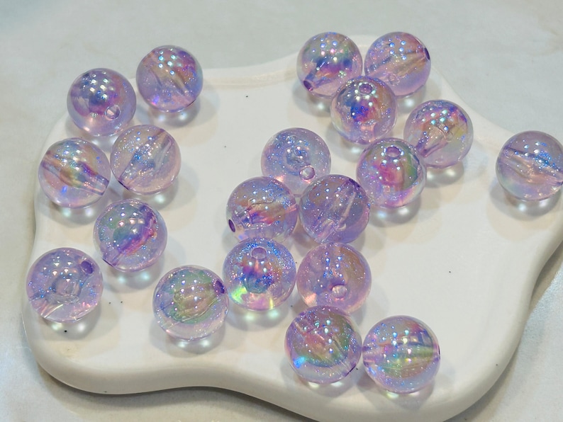 May include: A collection of iridescent purple glass beads. The beads are round and have a shimmery finish.