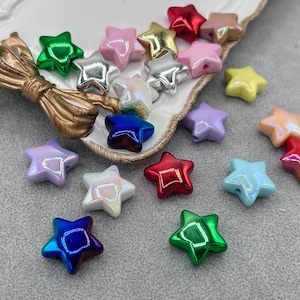 May include: A collection of star-shaped beads in various colors, including red, blue, green, pink, and iridescent. The beads are made of glass or plastic and have a smooth, shiny finish.