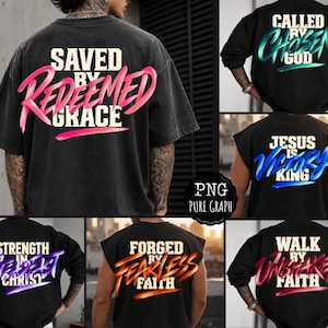 May include: A collection of black t-shirts featuring various religious phrases in bold, stylized lettering. Designs include Saved by Grace, Called by God, Jesus is King, Strength in Christ, Forged by Faith, and Walk by Faith in vibrant colors.