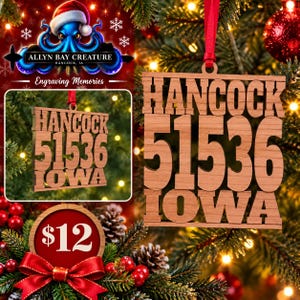 Puede incluir: Un adorno navideño cuadrado de madera con el texto HANCOCK, el número 51536 y la palabra IOWA cortados con láser y apilados verticalmente. El adorno es de madera marrón clara y cuelga de una cinta roja fina sobre un fondo festivo borroso.