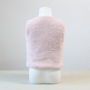 May include: A soft, pink, fluffy vest with no sleeves.