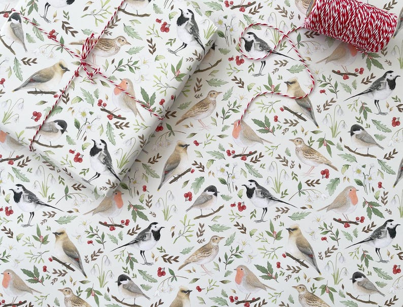 May include: White wrapping paper with a repeating pattern of birds, berries and leaves. The birds are white with black accents and are depicted in various poses. The berries are red and the leaves are green.