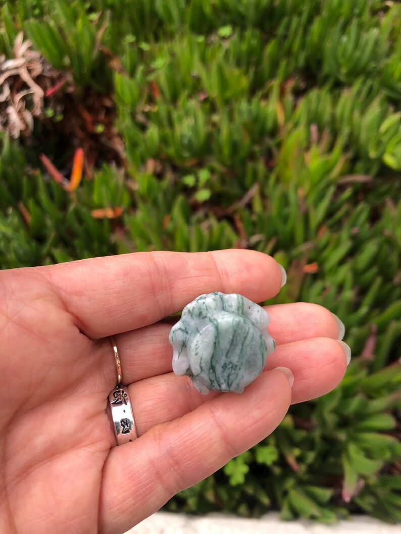May include: A green and white agate stone with a swirling pattern. The stone is smooth and polished.